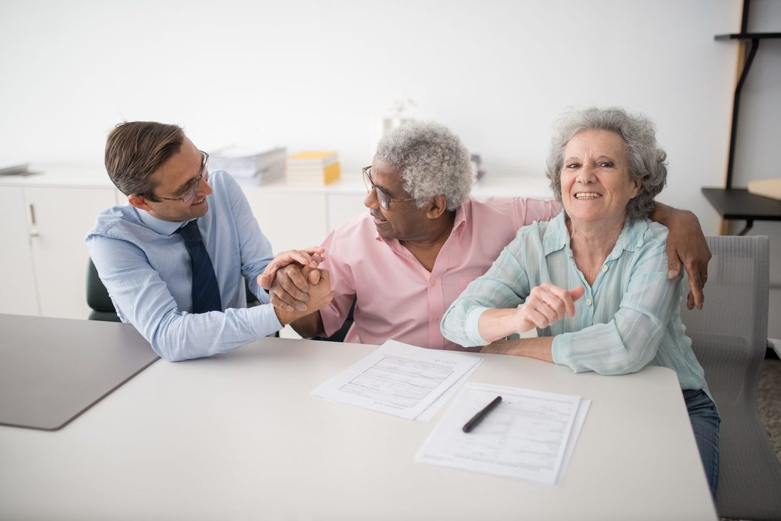 An advisor reviewing financial documents with two smiling clients