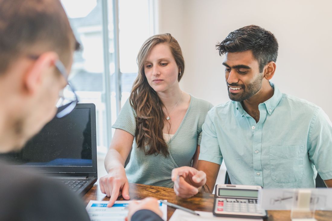 A young couple reviewing financial paperwork with an advisor
